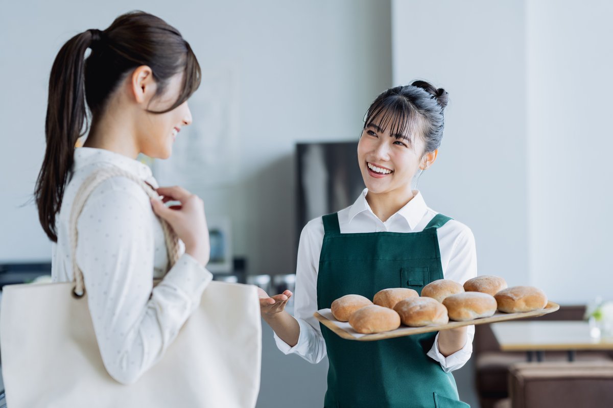 パン屋でお客様と笑顔で接客する店主。紙の回数券管理の煩わしさから解放されたい